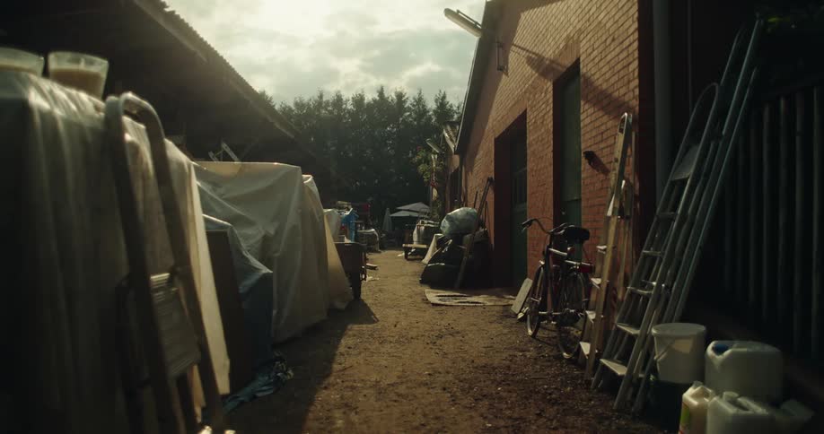 Corridor between sheds filled with items covered by tarps on a summers day