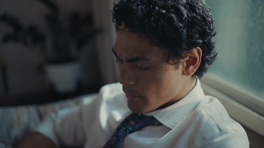 Close up of a man sitting in front of a window thinking to himself