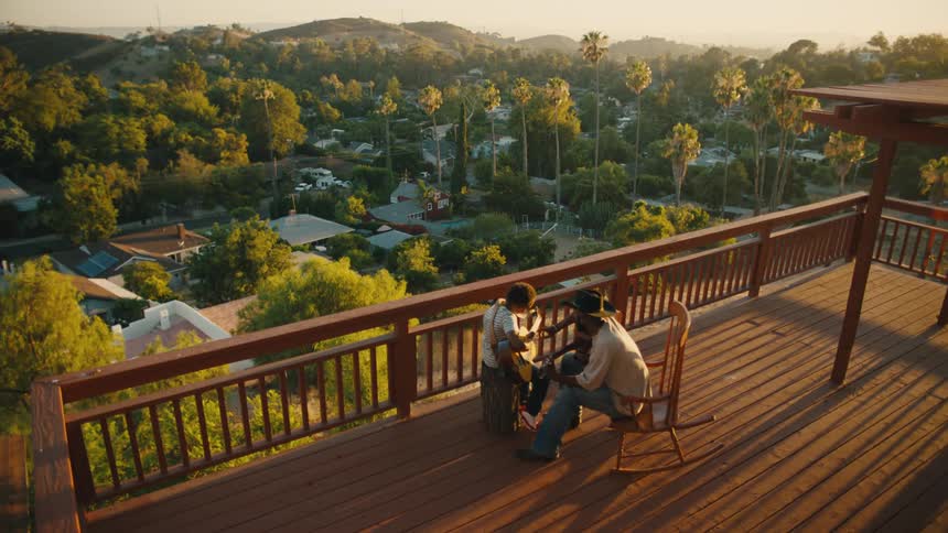 Man and a boy sitting on a balcony playing guitar