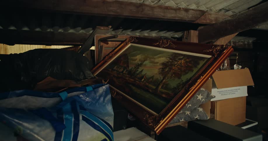 Large landscape painting stored in a shed surrounded by items