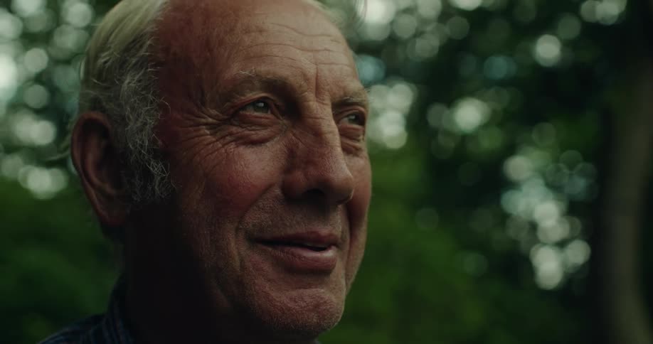 Portrait of an elderly man looking happy with trees in the background