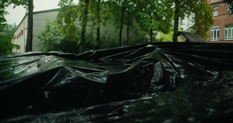 A black plastic tarp covering an object outdoors from the rain