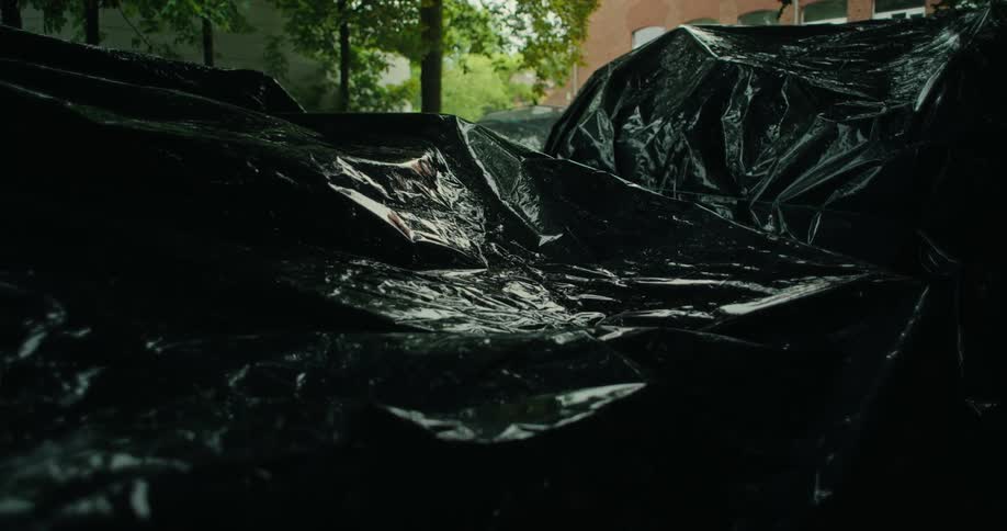 Several black tarps with a wet surface