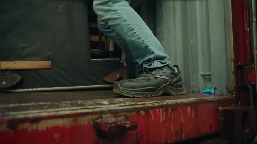 Feet of a man inside a truck pushing a piece of furniture