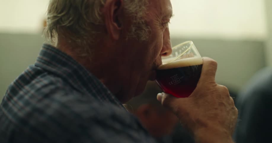 Elderly man sitting drinking a glass of beer with friends