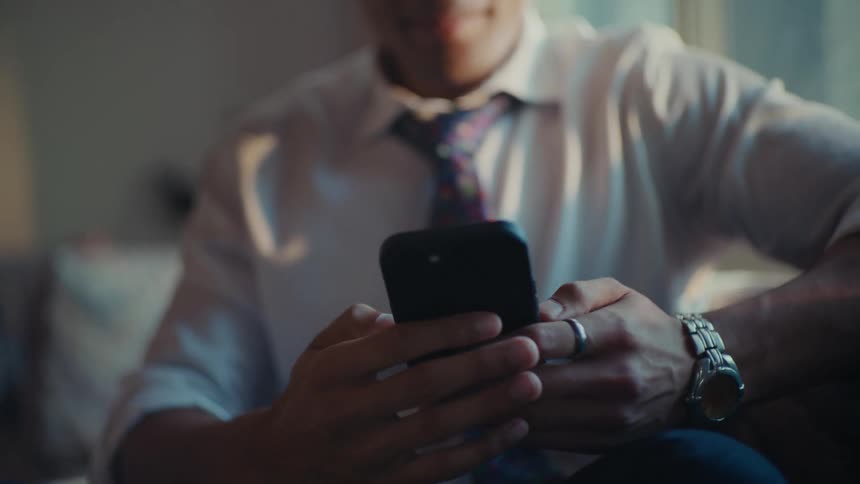 Man with happy facial expression sitting interacting with an iphone