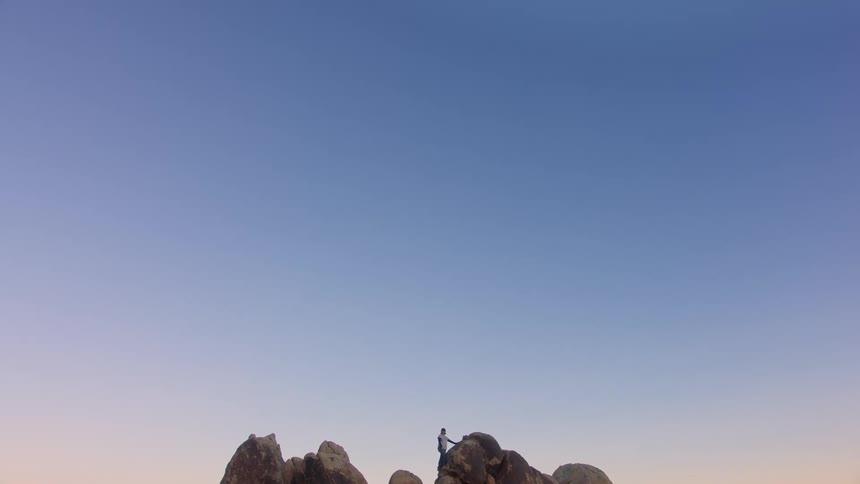 A person climbing to the top of a rock formation