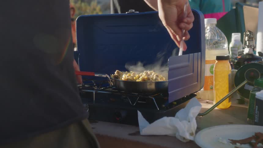 Hands of a person cooking on a mobile outdoor stove
