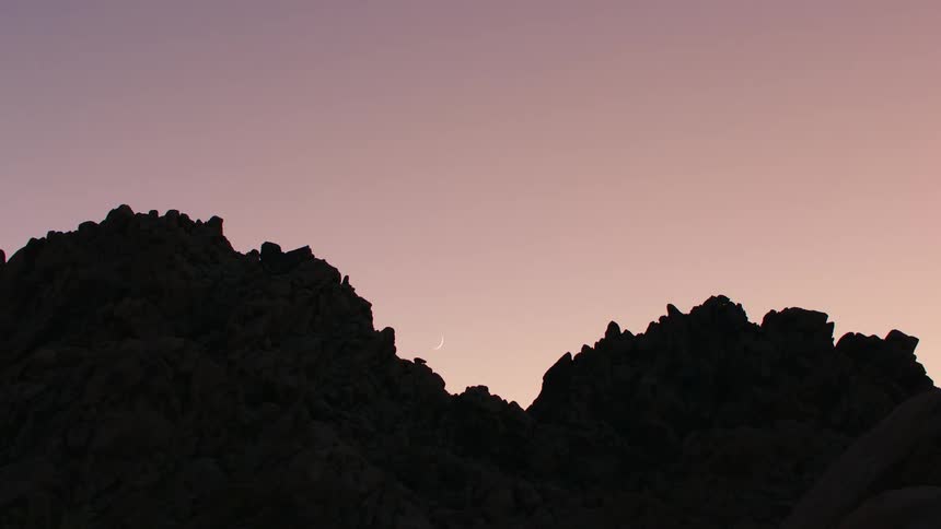 Silhouette of jagged mountain peaks against a twilight sky with hues of pink and purple