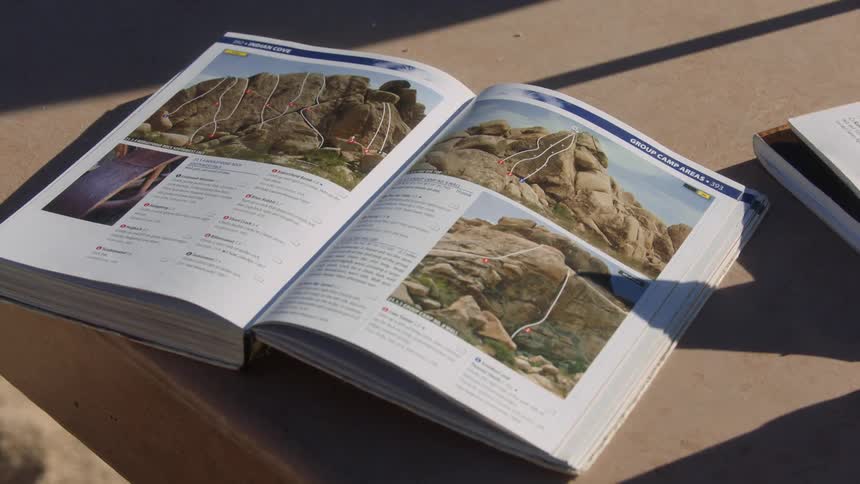 Open book displaying images and text lying on a wooden bench outdoors