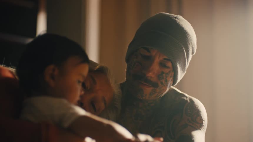 A grandmother holding her infant granddaughter while the father sits next to them holding the babies hand