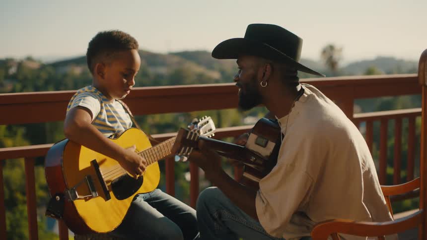 Man in hat playing guitar next to another little boy holding a guitar