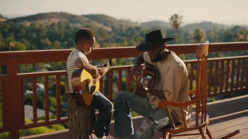Man in hat and a boy sitting touching hands and start playing guitar