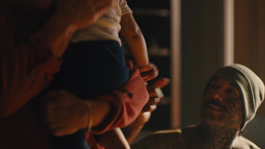 Woman with a baby on her lap and the father sitting interacting