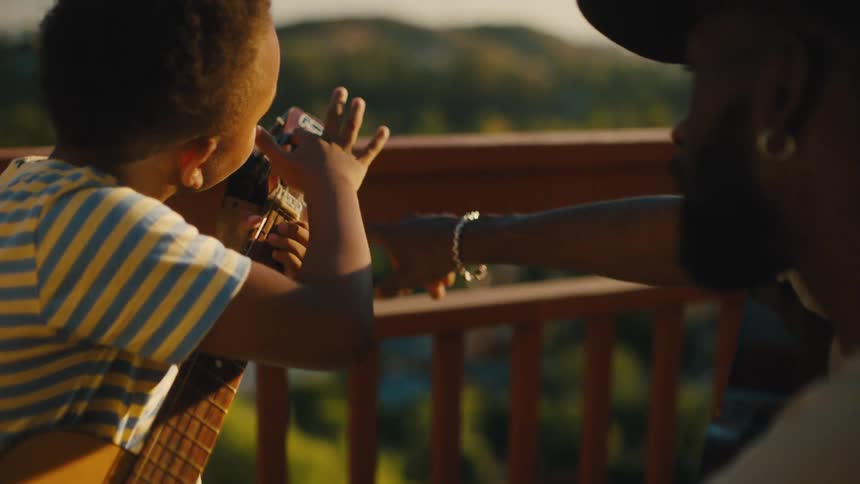 Man helping a boy tune the strings of a guitar