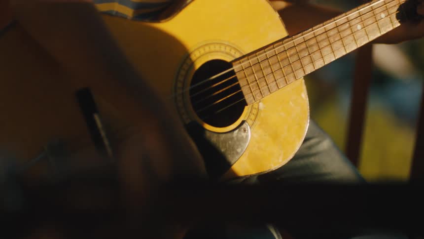 Guitarist taps his foot while playing an acoustic guitar outdoors