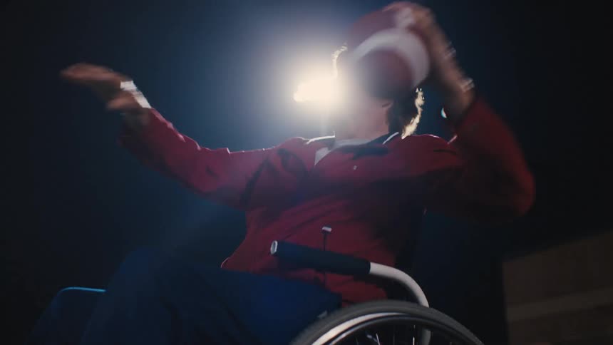 Person in a wheelchair picking up a football and throwing it again