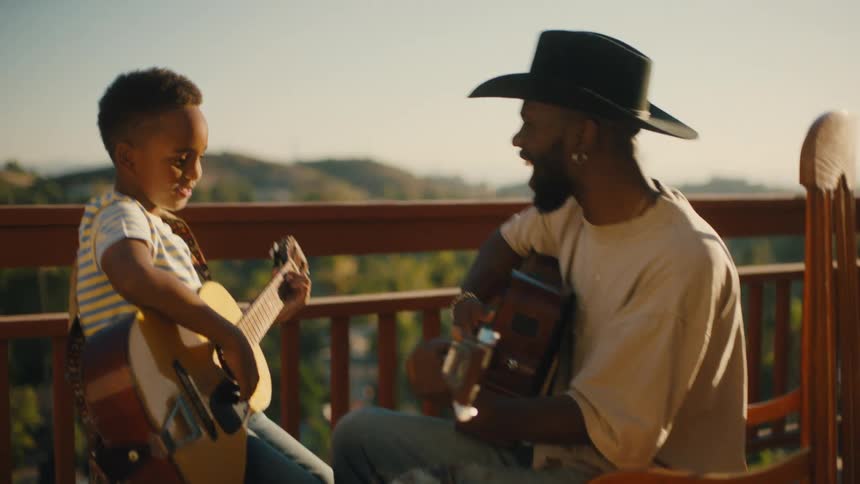 A father in a cowboy hat sitting on a porch with his son both holding guitars and playing on them