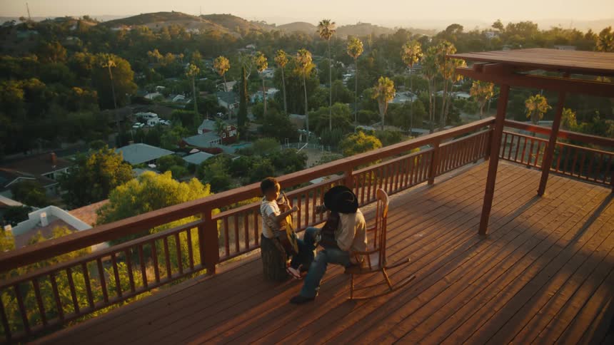 Father and son playing guitar on a wooden deck during sunset highfiving each other