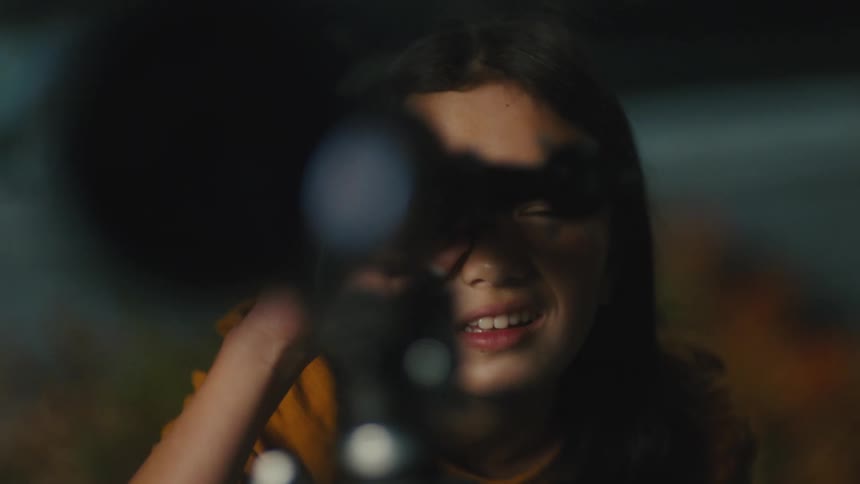 A mother shows her daughter how to use a telescope as the girl looks through the lens