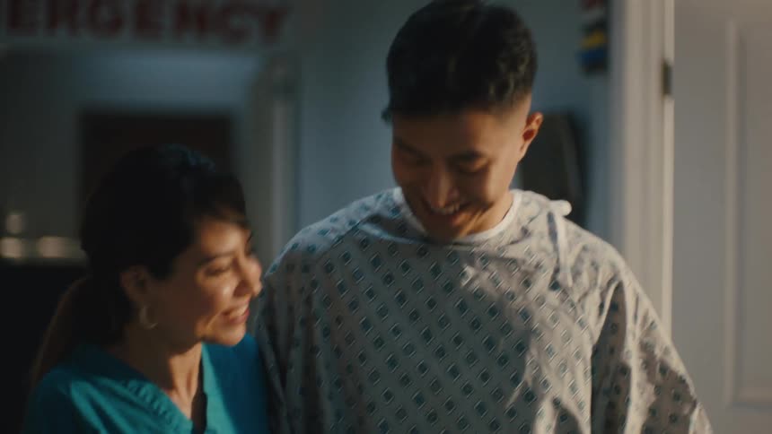 Nurse helping a young man walk down the hospital corridor