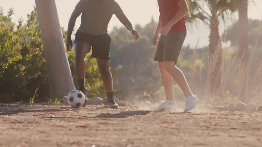 Two teenagers on a dirt road playing soccer