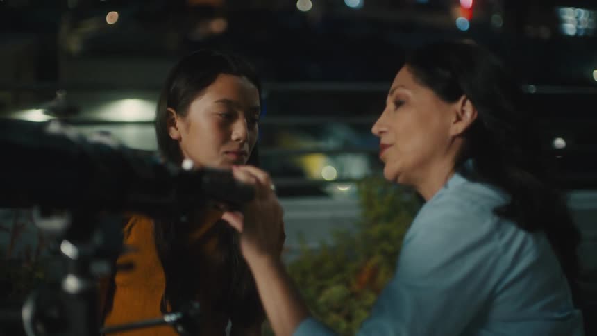 Mother and daughter looking through a telescope in the city at night
