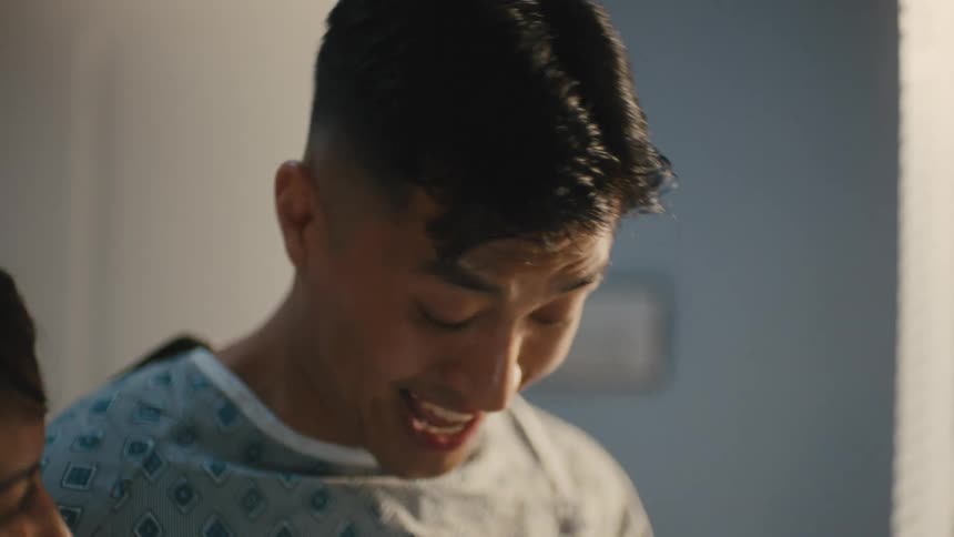 Closeup of a patients face as he walks with a nurse in a hospital corridor