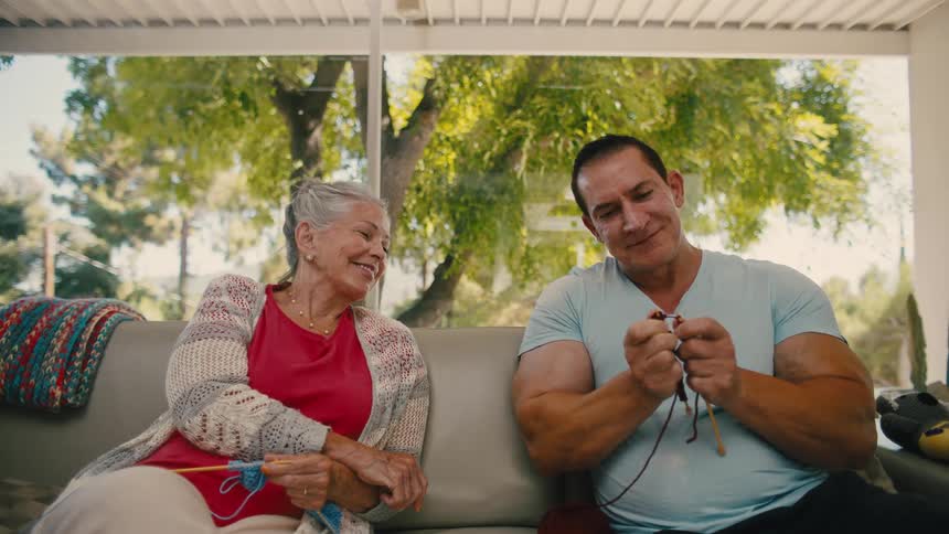 Elderly woman watching a man next to her sewing