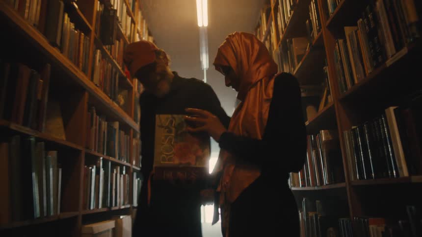 Elderly man and woman in the hallway of a library full of books
