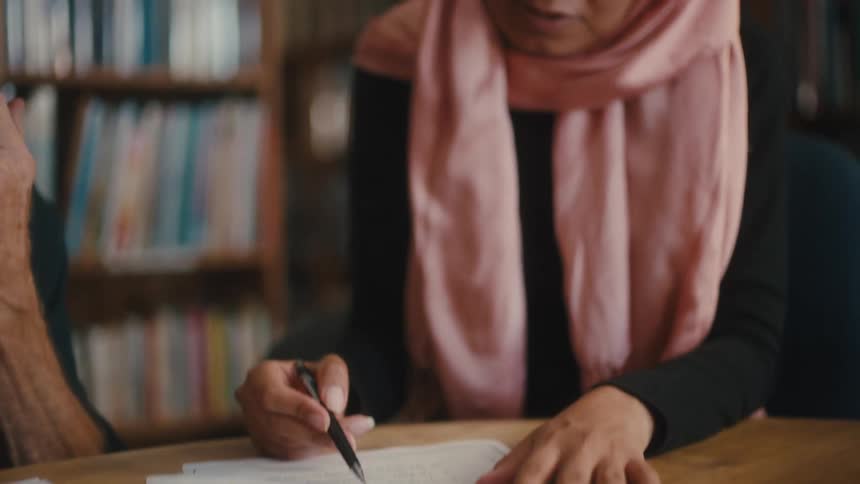 Concentrated woman sitting at a desk with a document and holding a pen