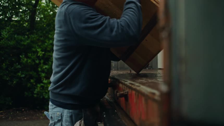 A man placing wooden furniture into the back of a loading truck