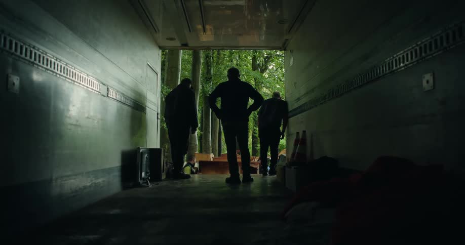 Silhouettes of men standing in the back of an empty moving truck