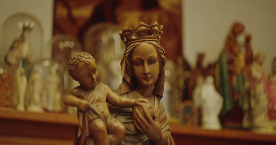 A carved woodern statue or a religious figure with more statues in the background