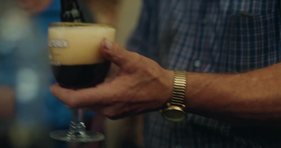 Close up of an older man pouring beer into a glass