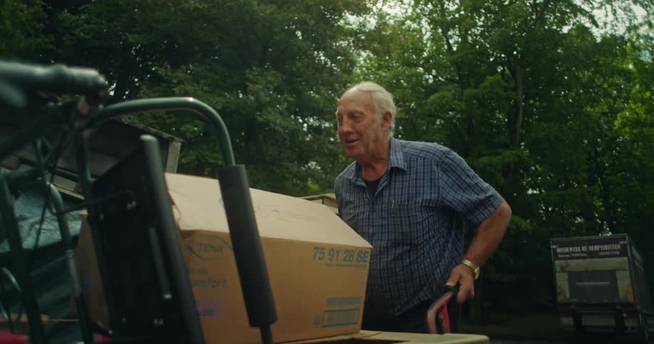 Elderly man carrying a cart with boxes