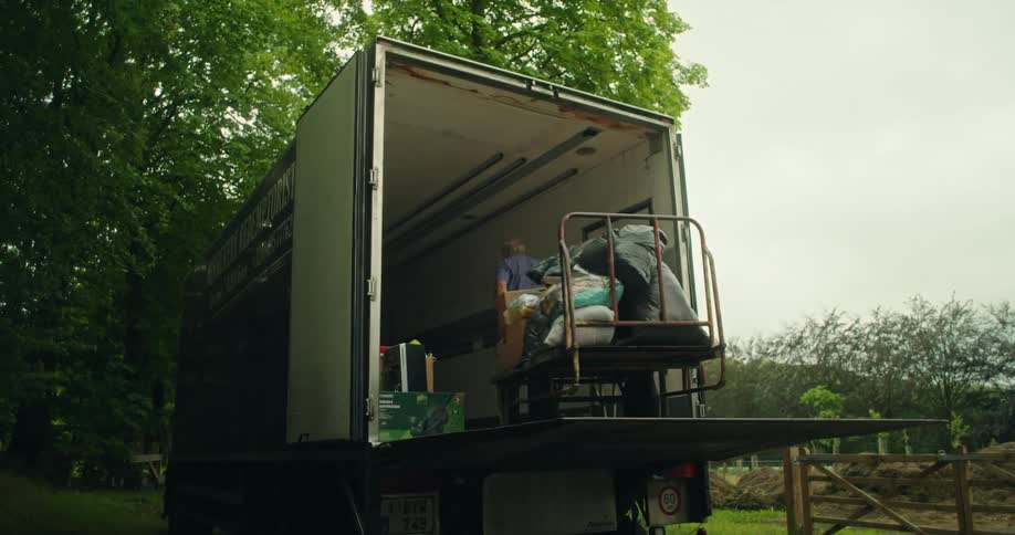 A man pulling a cart loaded with bags and boxes into a moving truck