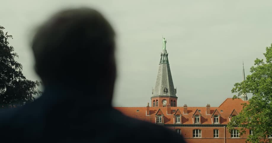 A person is sitting looking at a church spire