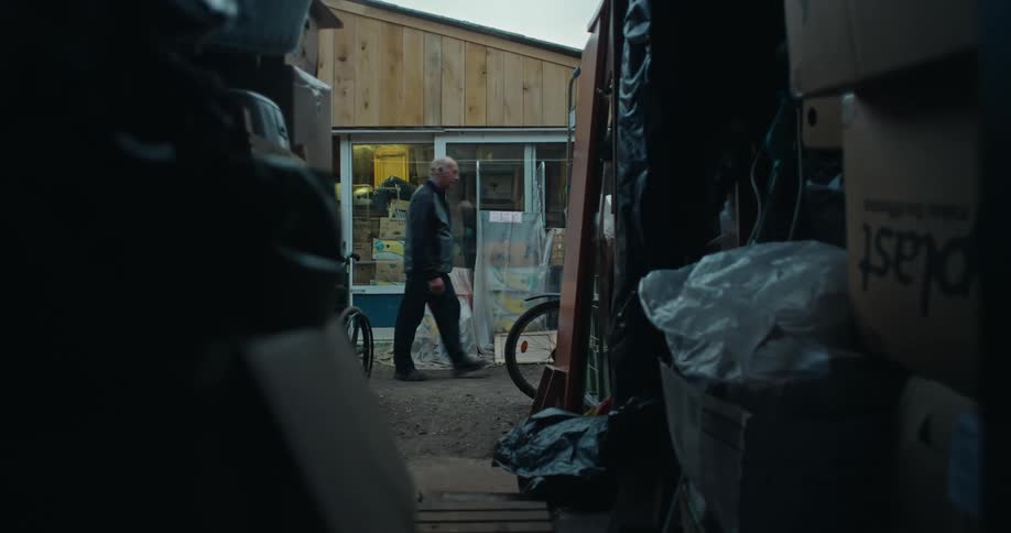 Corridor with boxes and debris with an elderly man walking in the background