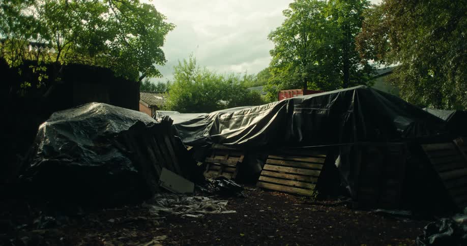 External area with black tarps covering debris with trees around