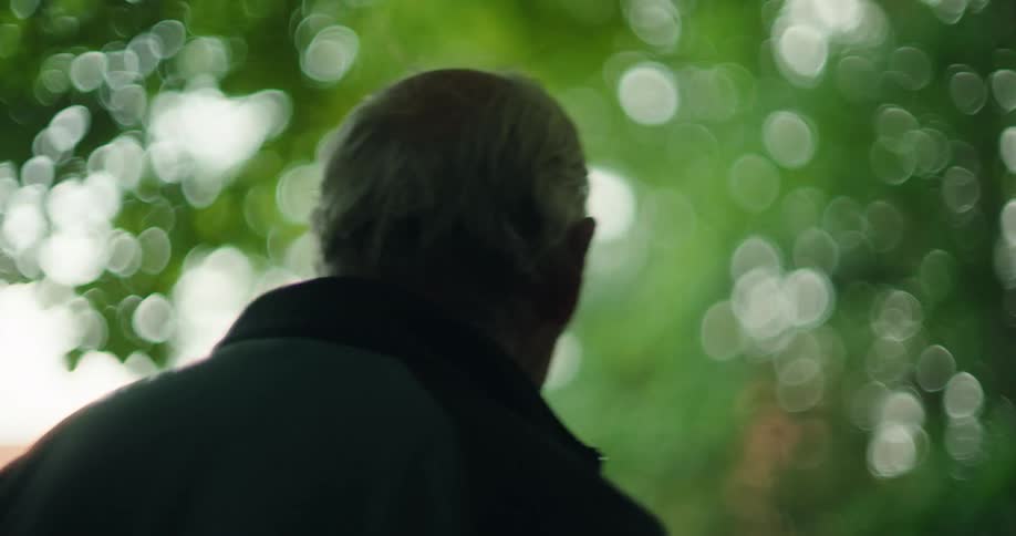 Elderly man walking in a forest with blurred trees in the background