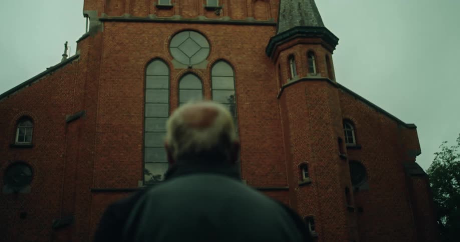 Back view of an elderly man looking up at a church