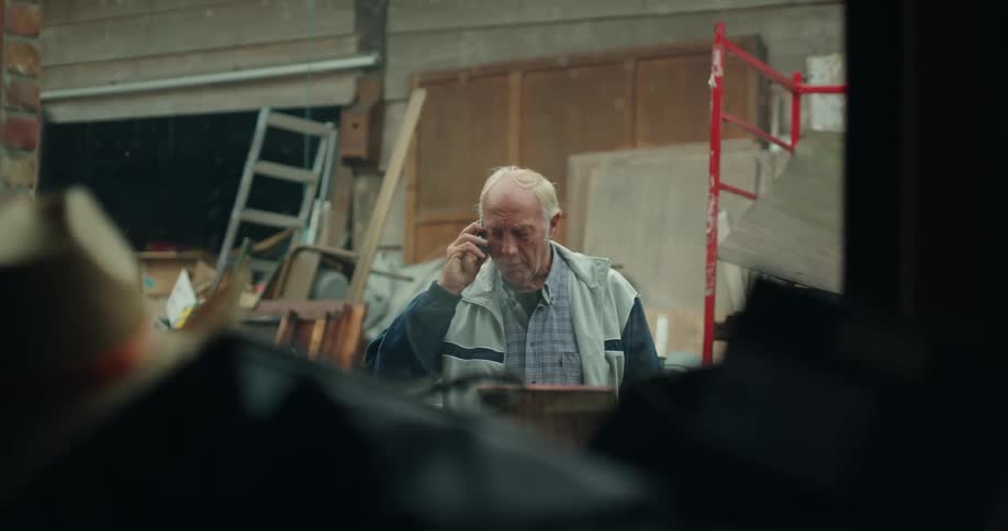Elderly man hanging up a call on a telephone