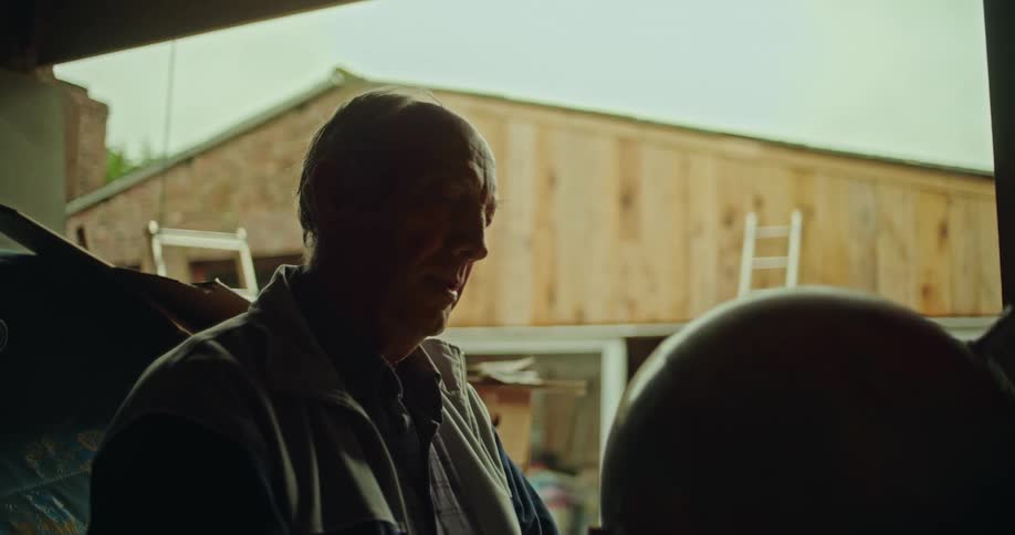 A man takes an earth globe down from a storage shelf and looks at it sadly