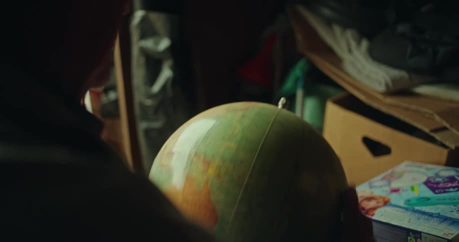 Elderly man picking up a scientific globe and brushes it with his hand