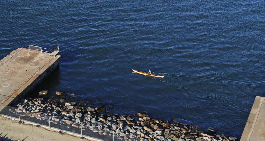Aerial view of a person in a canoe moving through the sea next to piers