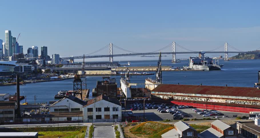 A busy port sits on a coast near a bridge leading into a downtown city