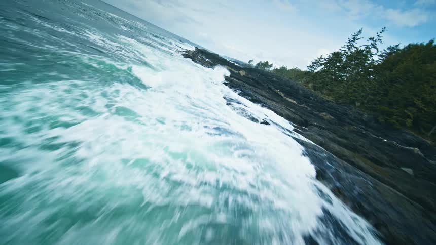 Large foamy waves crash against a rocky coastline