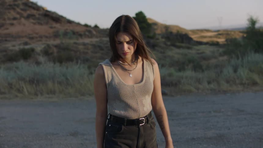 Woman walking on a gravel road in the hilly countryside stops to look around