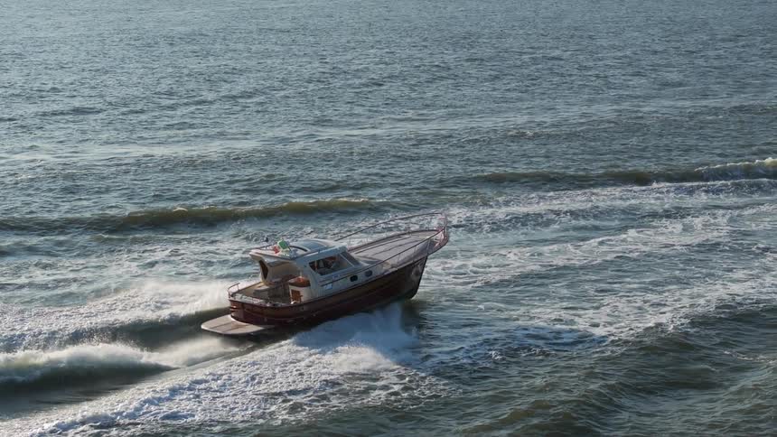 Aerial view of a boat moving through the sea with a city on the horizon